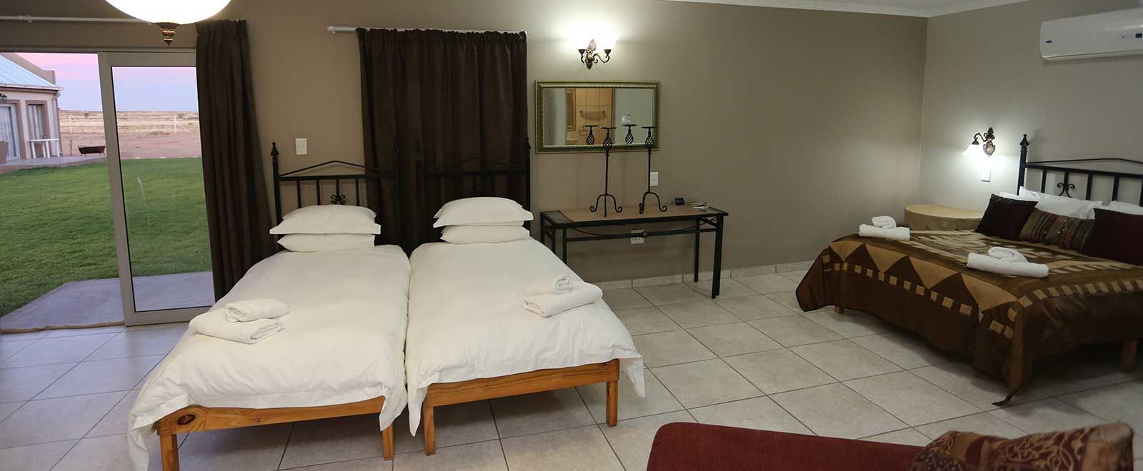 Inside a chalet: beds, kitchenette and glass sliding door