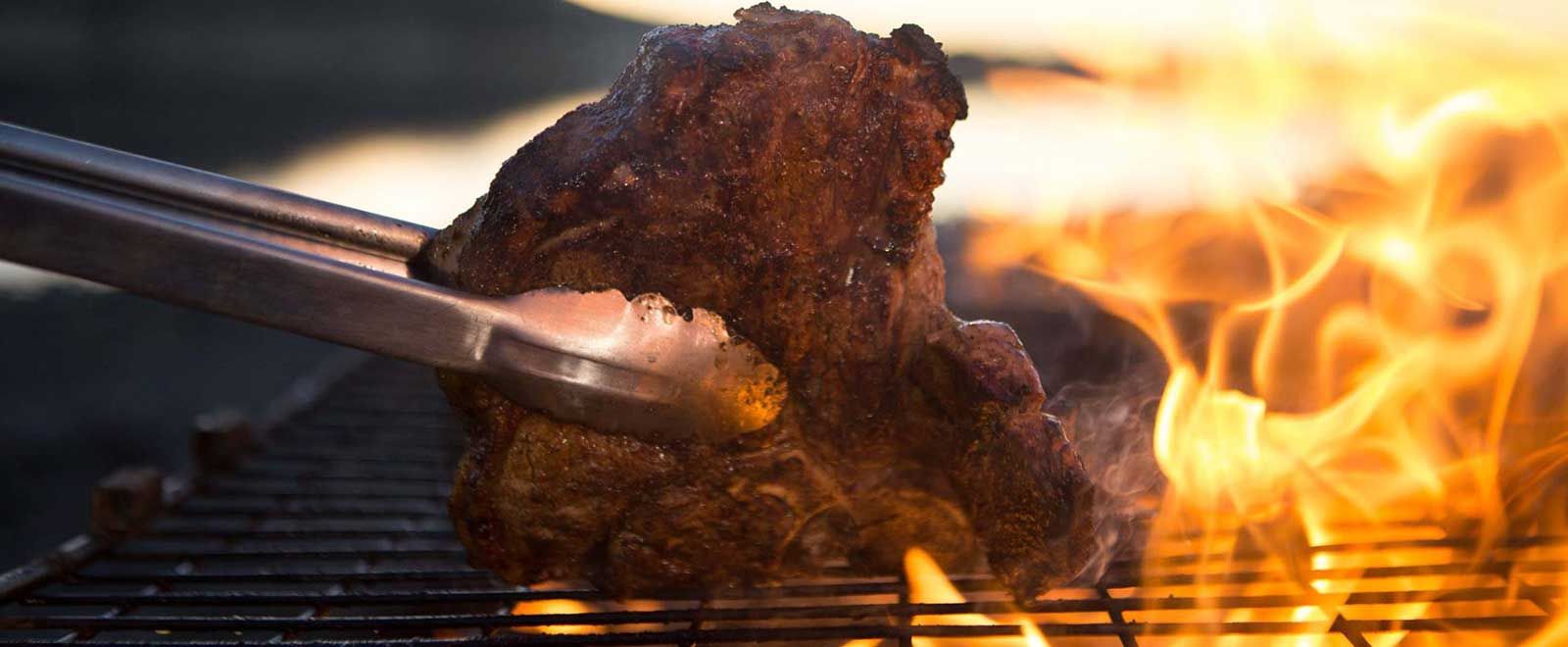 Meat sizzling on a braai grid over open flames