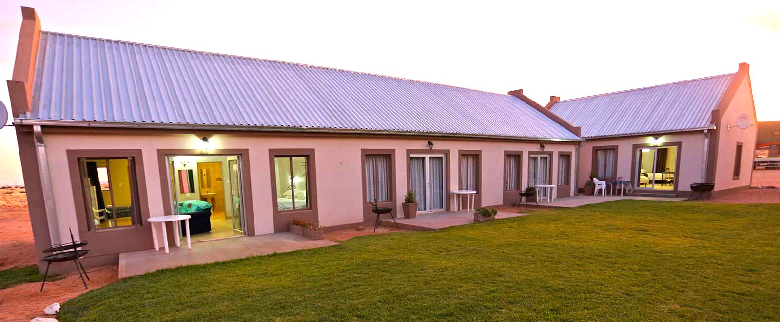 Grünau Chalets at dusk — the row of self-catering chalets with lawn in front