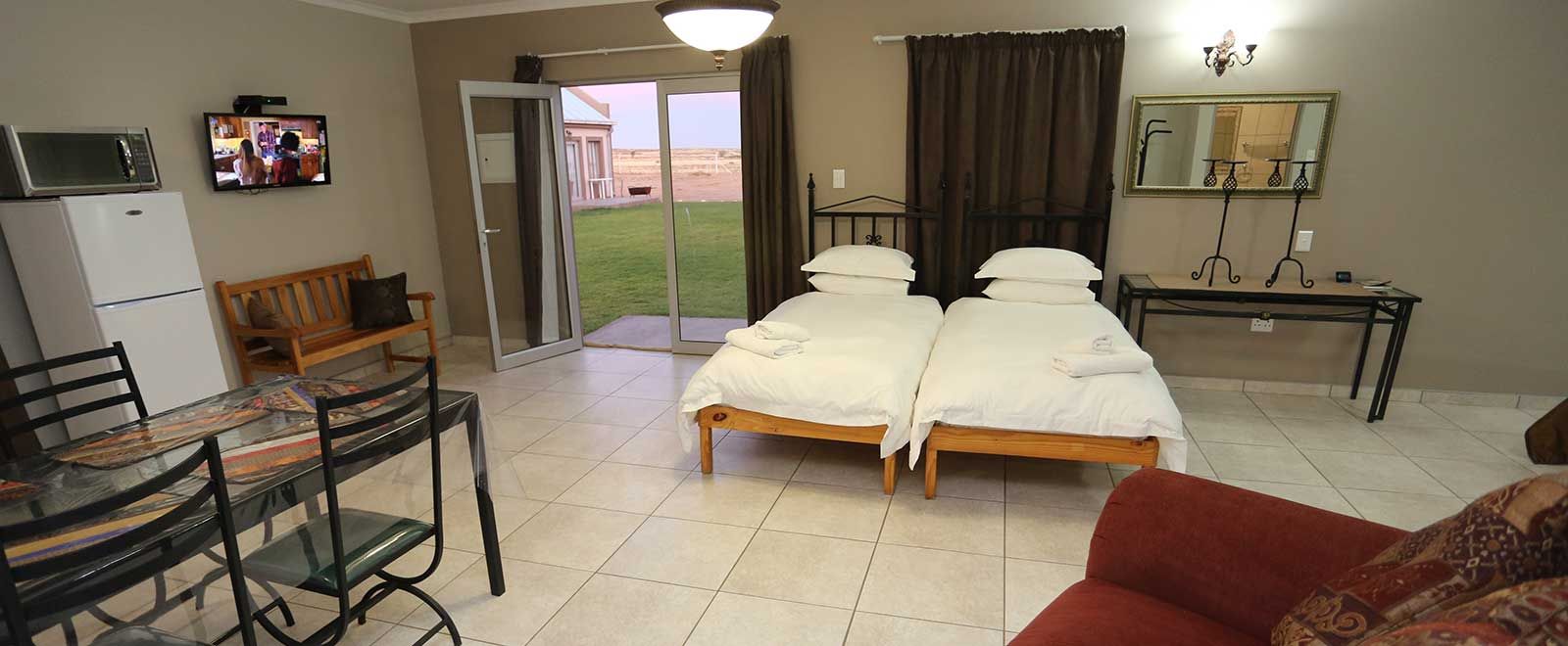 Family room with multiple beds, kitchenette and TV at Grünau Chalets